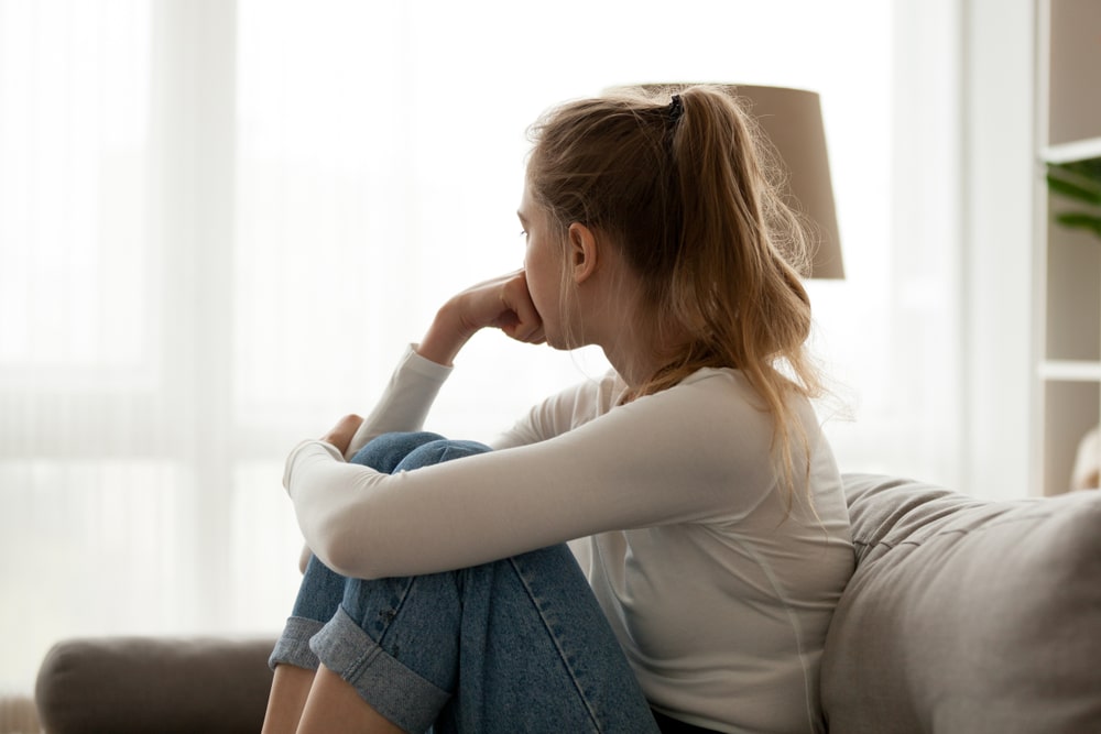 A young woman sitting alone on a couch looking away