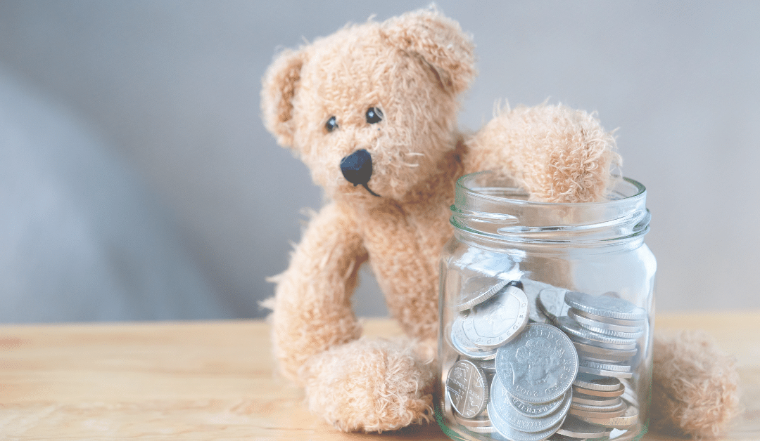 A teddy bear with it's arm in a jar of money