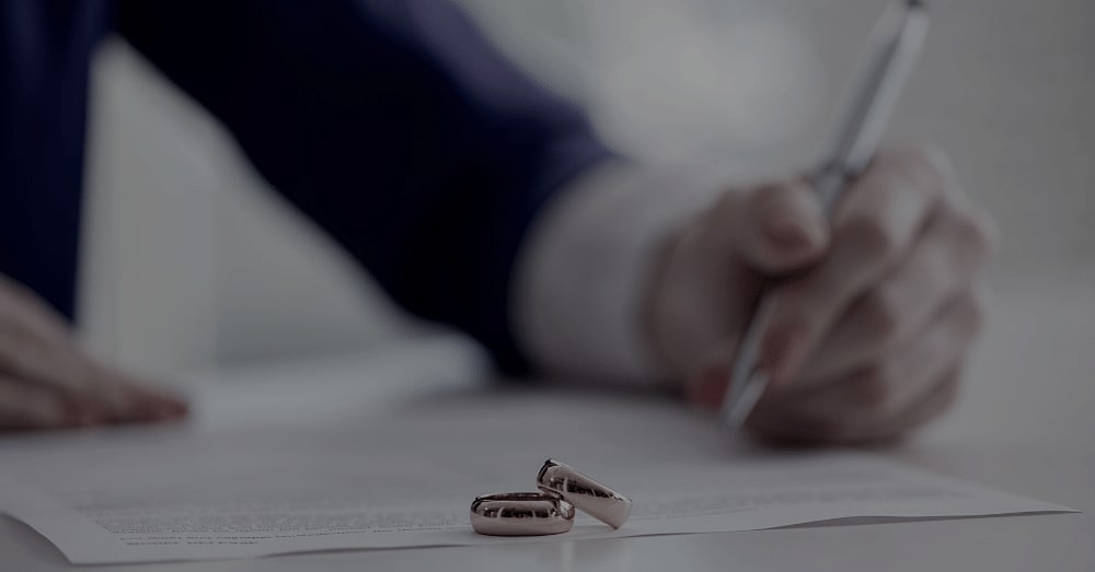 A woman signing documents with wedding rings