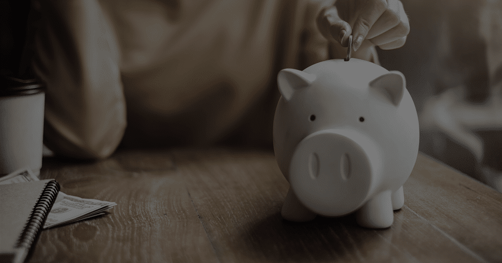 A woman dropping money into a piggy bank