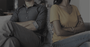 A couple crossing arms in opposite direction on a couch